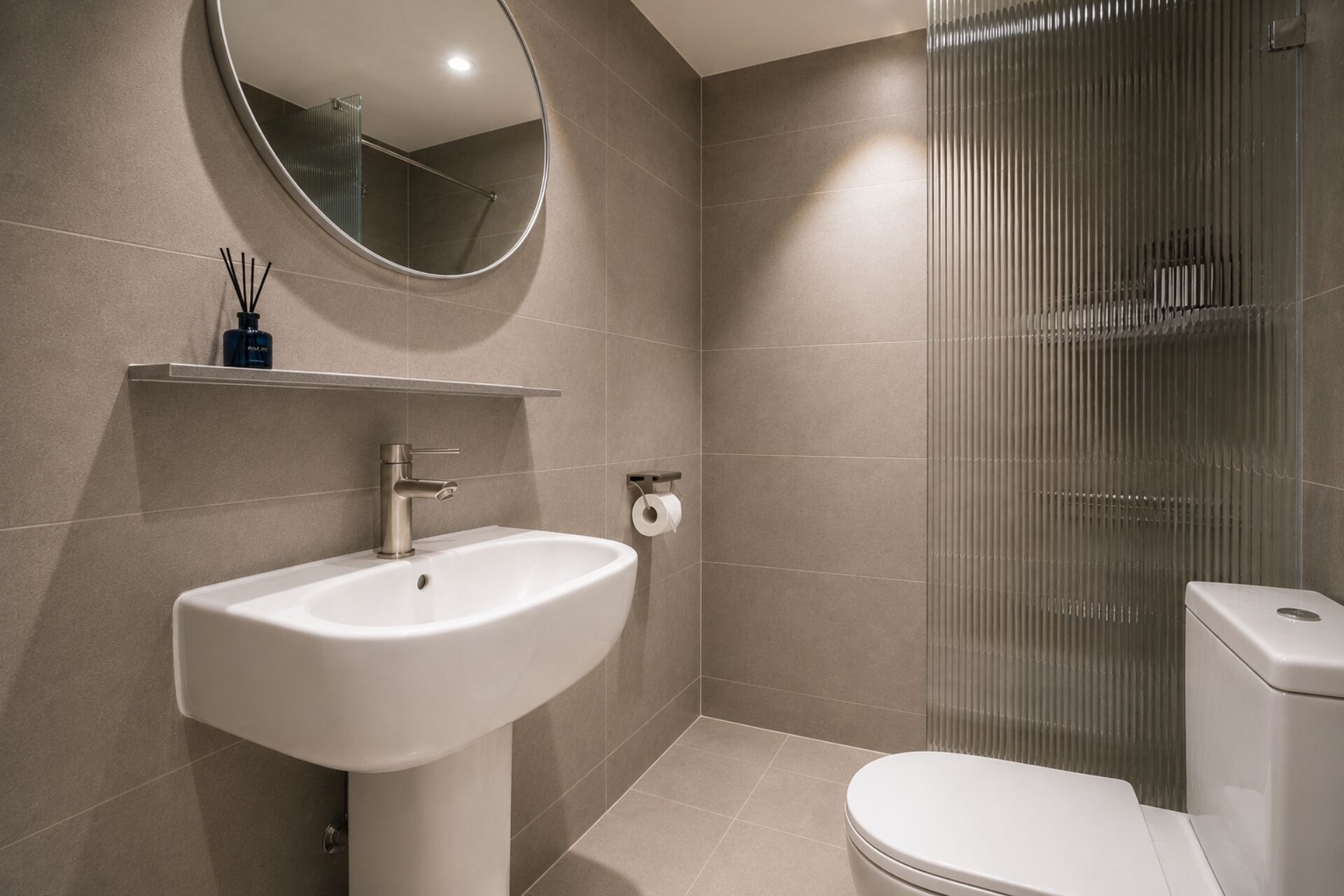 A modern bathroom with a sink, toilet, and shower enclosure.
