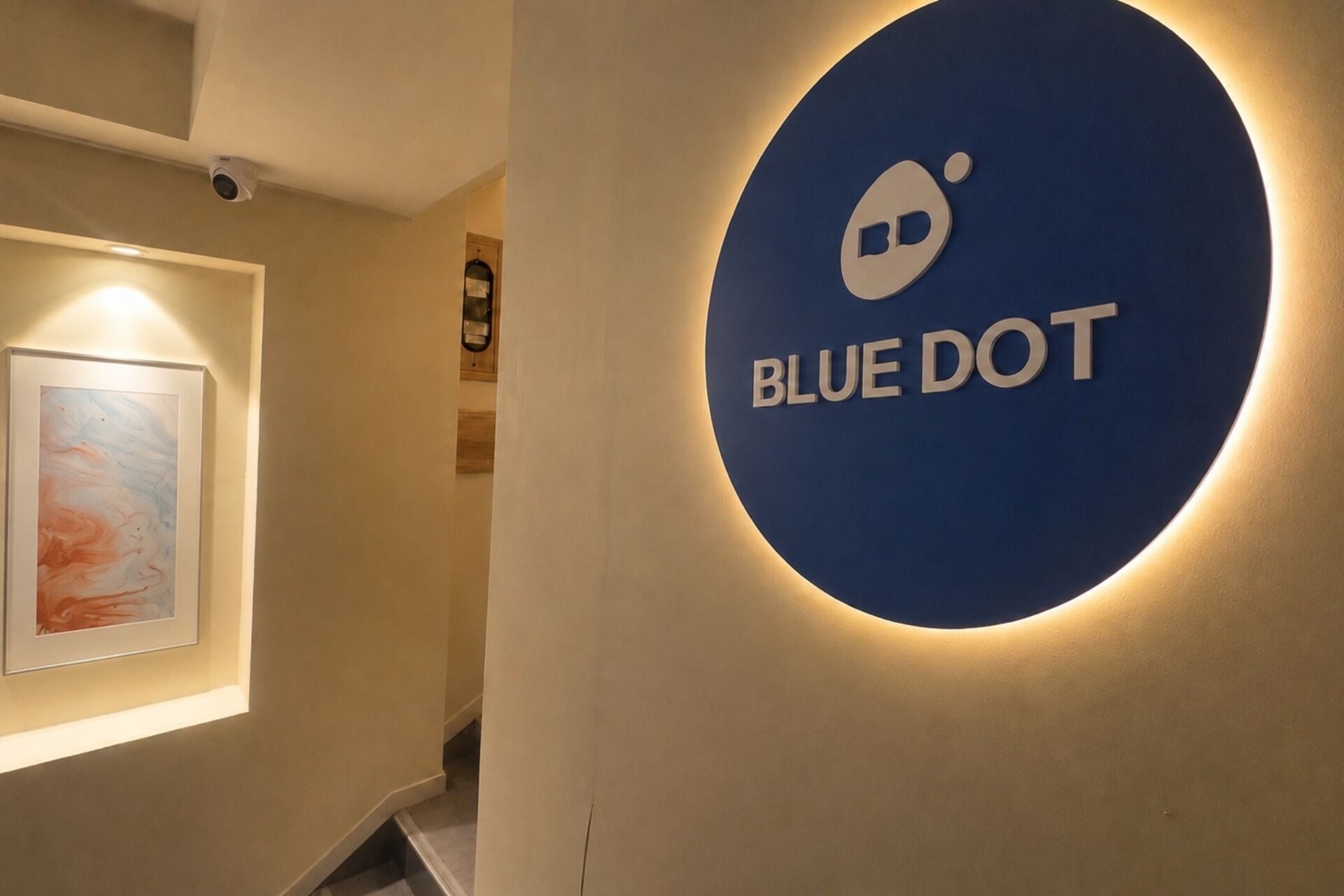 Um corredor com um sinal Blue Dot, uma obra de arte emoldurada e uma escada.