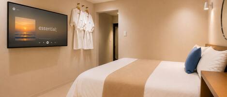 A hotel room with a bed, a TV on the wall, and a robe rack.