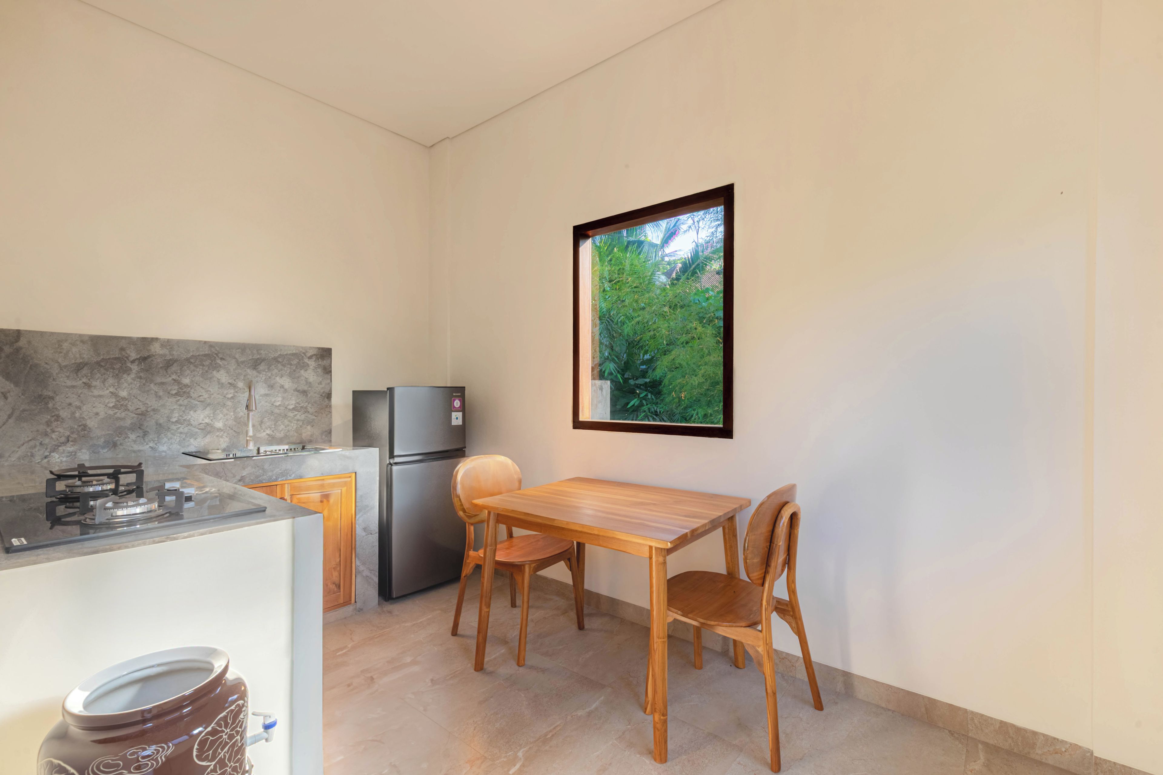 Una cocina compacta con estufa a gas, refrigerador y una mesa de madera con sillas.
