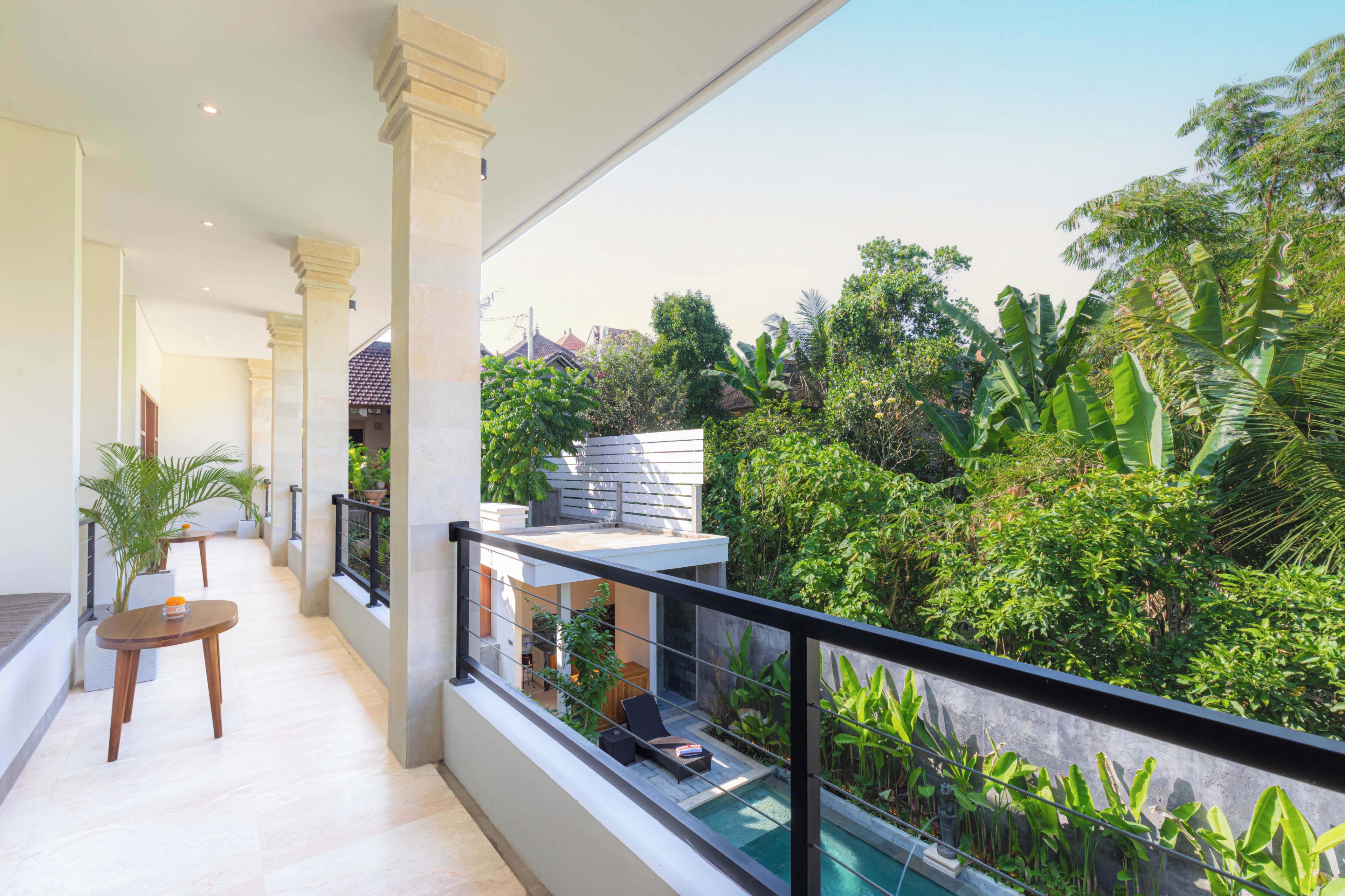A balcony with a pool, surrounded by lush greenery and a view of a residential area.