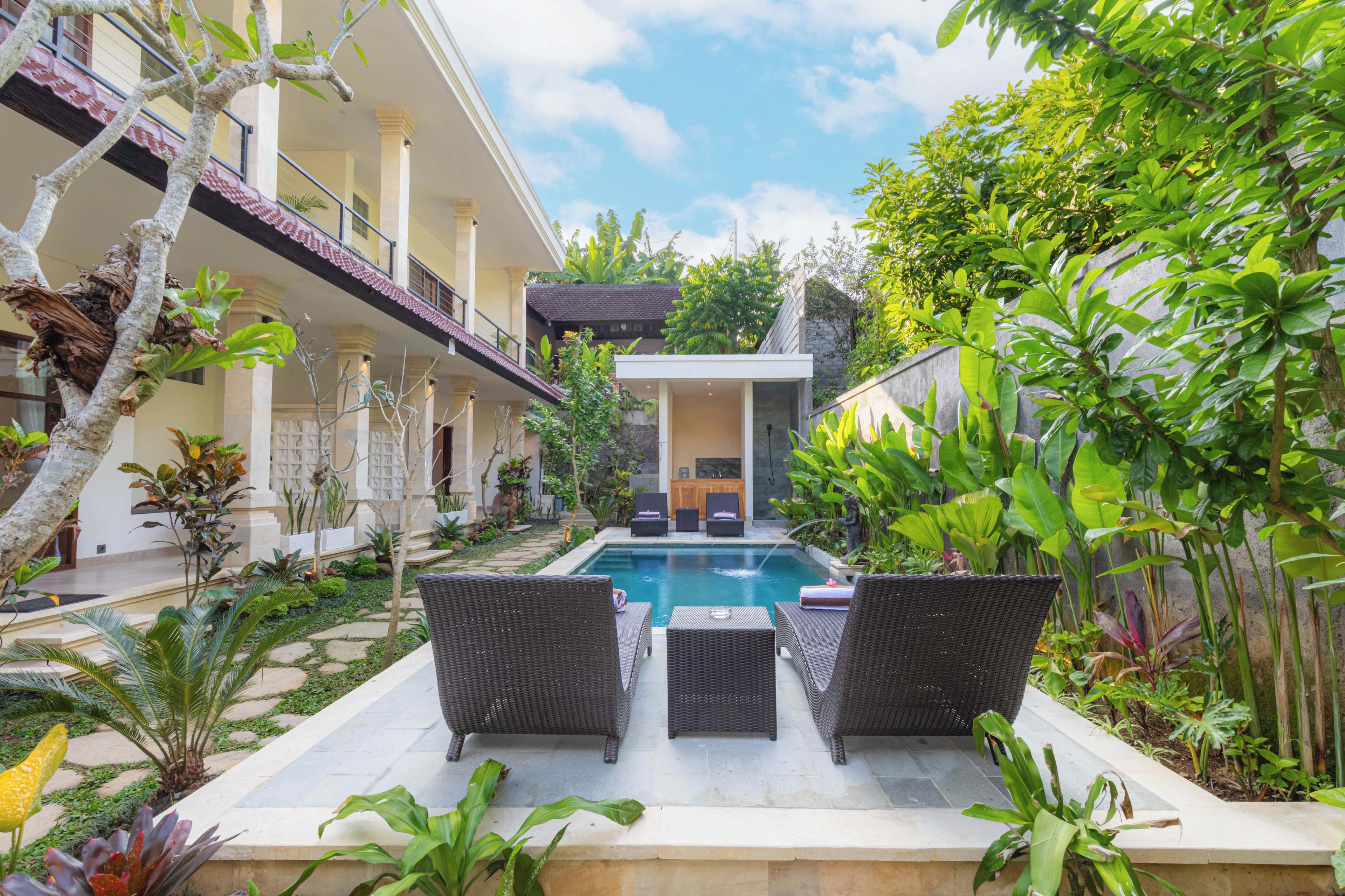 A pool area with lounge chairs and a view of a building with columns.