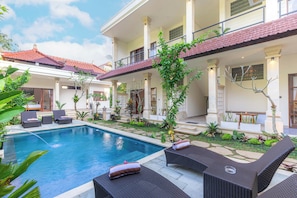 Área de piscina com espreguiçadeiras e um terraço coberto.