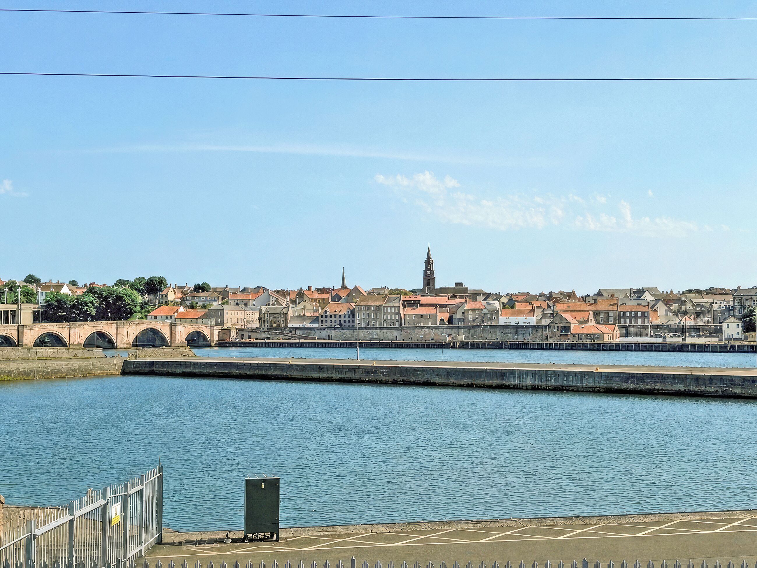 A waterfront view of a city with a prominent tower and a bridge.