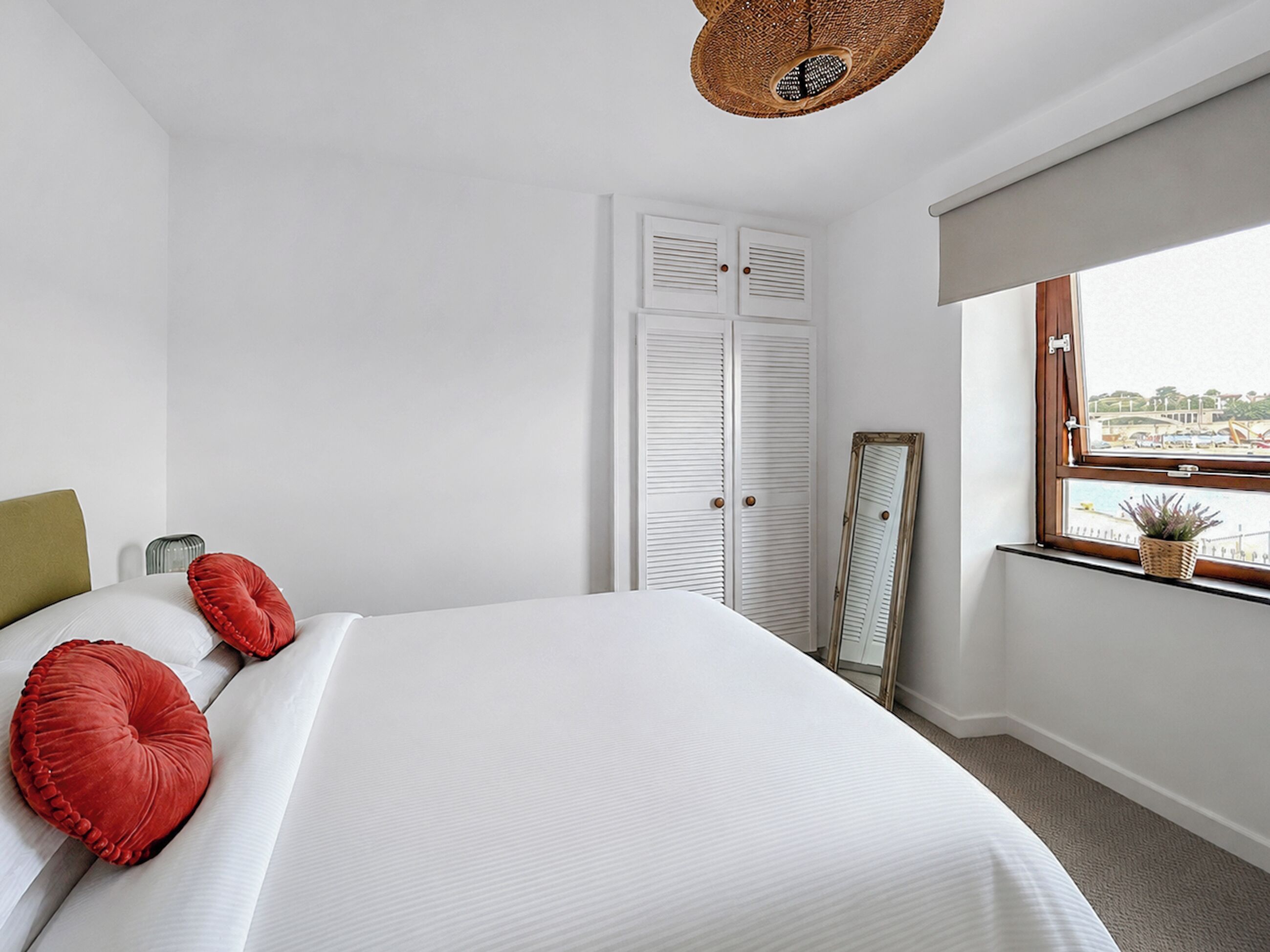 Una habitación de hotel con cama, ventana con vistas, armario y espejo.