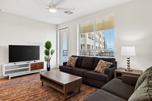 A modern living room with a flat-screen TV, a sofa, a coffee table, and a lamp. - Rooftop Pool + Gym + Sauna + Spa | Desert Ridge + TPC Golf | Azur by AvantStay (Phoenix)