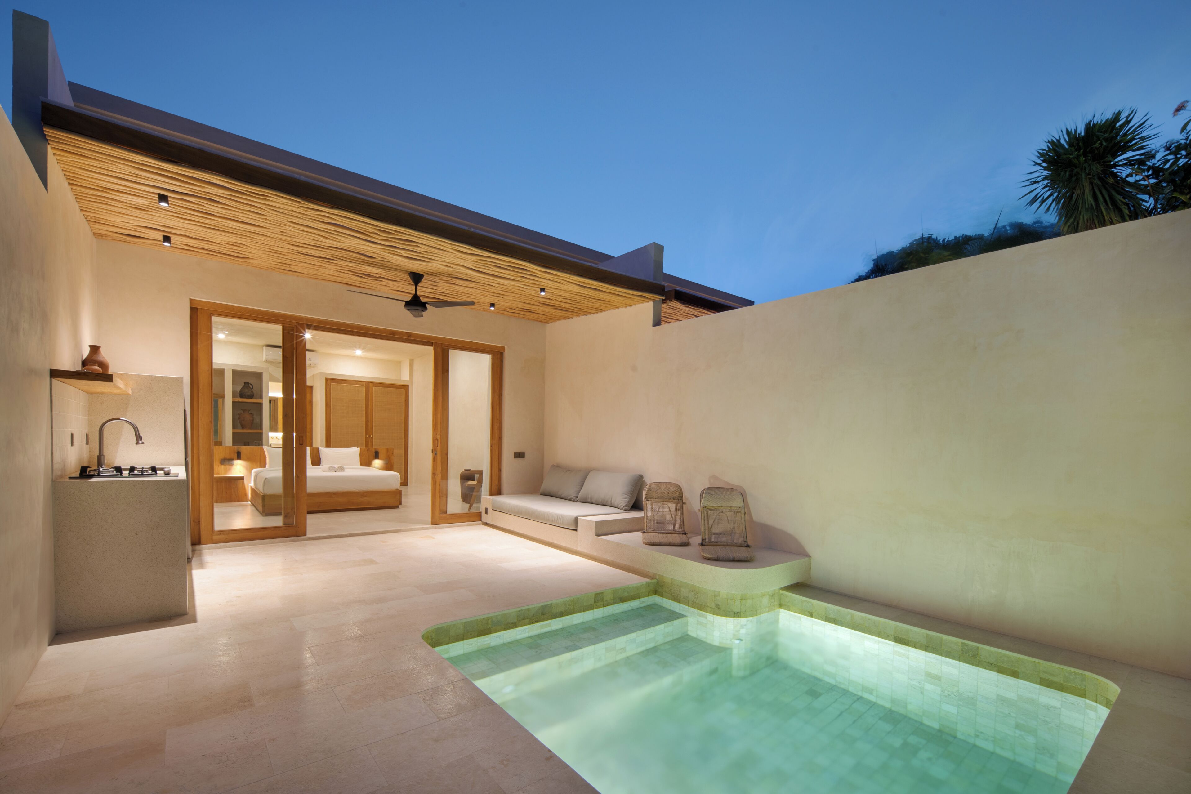 A modern outdoor bathroom with a pool, a sofa, and a bed.