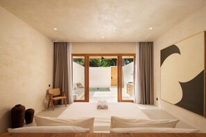 A modern bedroom with a large bed, a view of a pool, and a wooden floor. - Nuba Villas (Lombok Tengah)