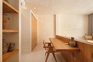 Una habitación minimalista con una mesa de madera, una silla y una estantería con cerámica.