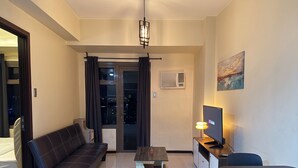 A modern living room with a sofa, a coffee table, a TV, and a painting on the wall.