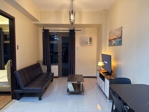 A modern living room with a sofa, a coffee table, a TV, and a painting on the wall.