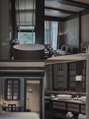 Une chambre d’hôtel moderne dotée d’une grande baignoire, d’un coin salon confortable, d’un bureau et d’une salle de bain séparée avec un grand lavabo.