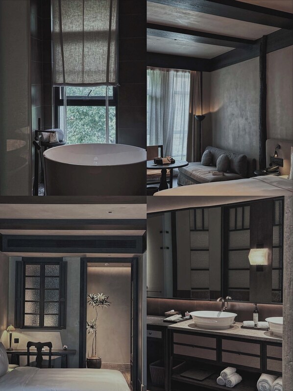 A modern hotel room with a large bathtub, a cozy seating area, a desk, and a separate bathroom with a large sink.