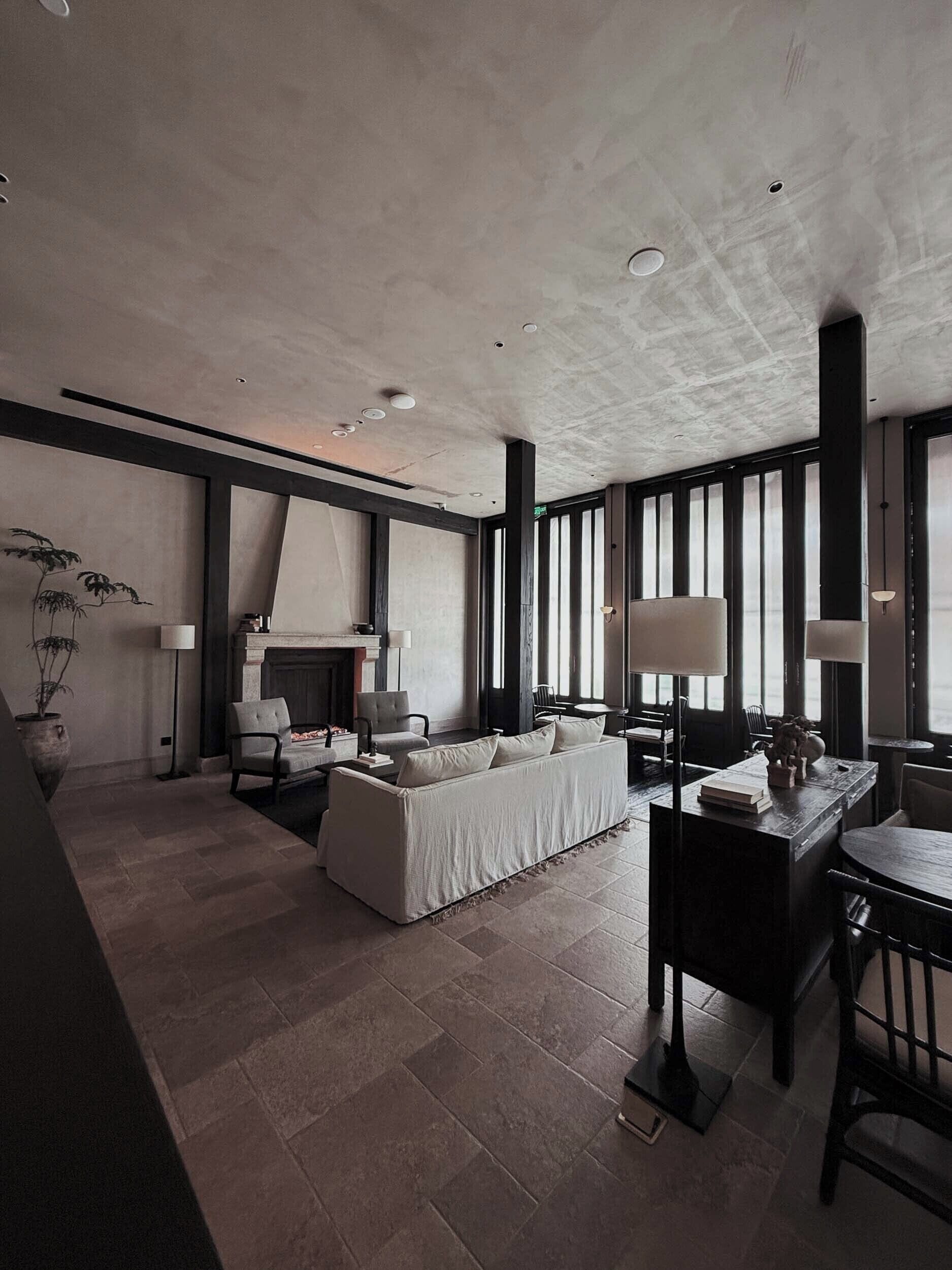 A modern living room with a fireplace, a sofa, a dining table, and a large window.