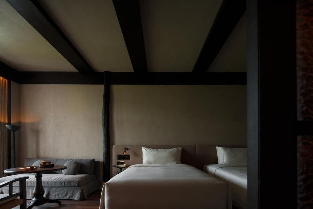 Una habitación de hotel con una cama, una mesita de noche, una lámpara y un sofá.