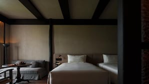A hotel room with a bed, a bedside table, a lamp, and a sofa.