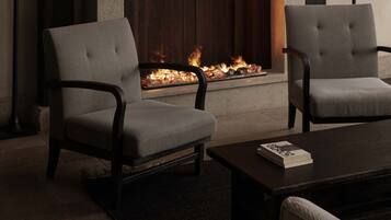 A room with a fireplace, two armchairs, a coffee table, and a lamp.