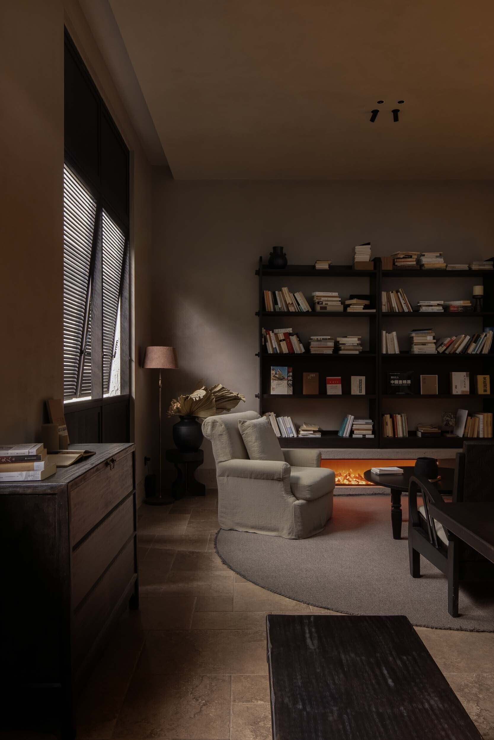 Una sala de estar acogedora con chimenea, una estantería y un sillón cómodo.