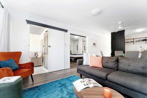 Ein modernes Wohnzimmer mit einer Couch, einem Sessel und einem Couchtisch mit einem Buch und einer Kerze.