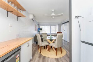 A modern kitchen with a dining area, a ceiling fan, and a built-in TV. - Fully Furnished Corporate Apartment (West End)