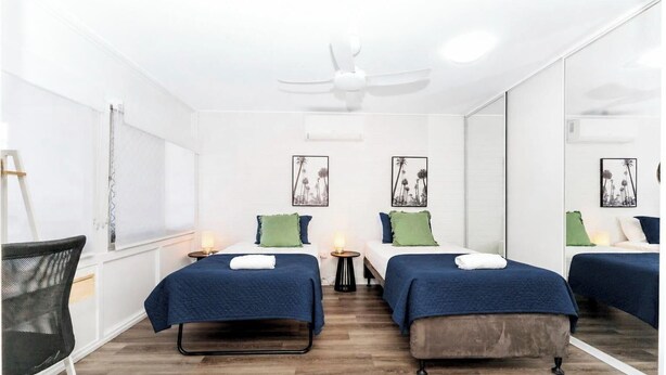 Ein Hotelzimmer mit zwei Betten, einem Deckenventilator und Kunstwerken an den Wänden.