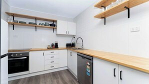 Eine moderne Küche mit weißen Schränken, Holz Arbeitsplatten und eingebauten Regalen.
