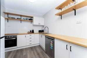 Eine moderne Küche mit weißen Schränken, Holz Arbeitsplatten und eingebauten Regalen.