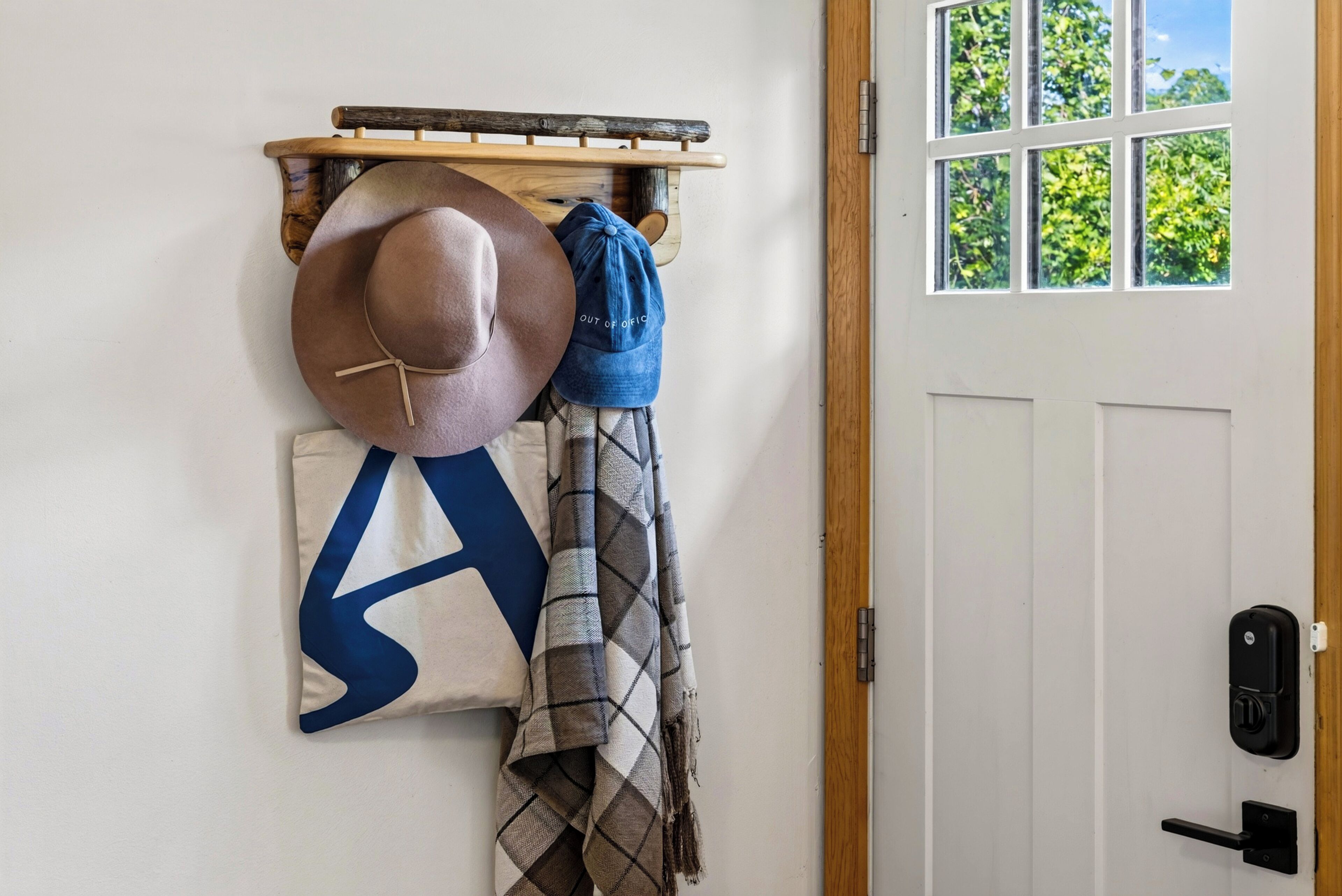 Eine Tür mit Fenster, ein Haken mit Hüten, ein Kopfkissen und eine Decke.