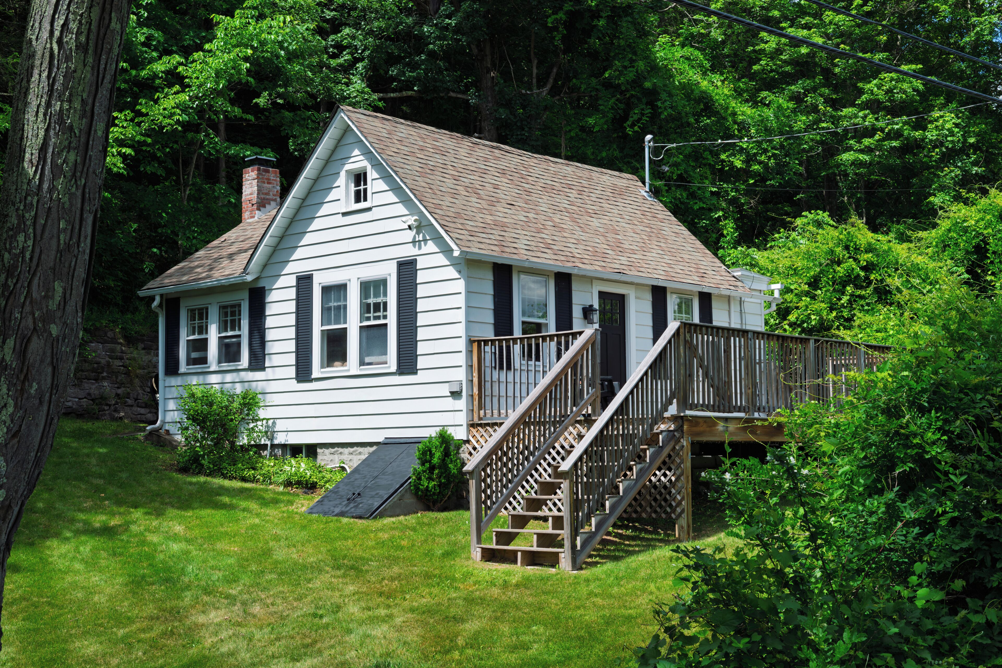 A white house with a wooden deck and a ramp leading to the entrance.