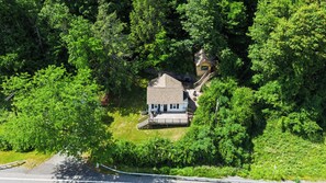 Ein Haus, umgeben von dichtem Wald, mit einer sichtbaren Terrasse und einer Treppe zum Eingang.