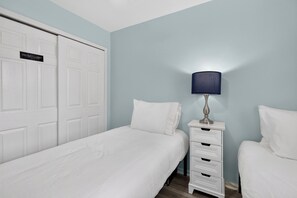 Quarto com cama, mesa de cabeceira, luminária e armário.