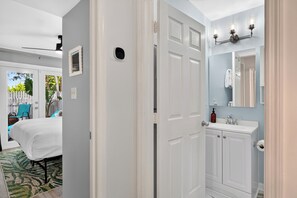 Habitación de hotel con cama, baño con lavabo y espejo, y vistas al exterior.