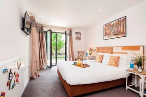 A hotel room with a large bed, a television, a painting, and a view of the outdoors. - The Akerman Road Hideaway (London)