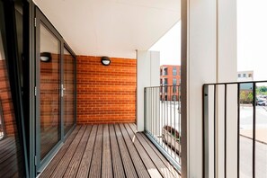 A balcony with a wooden floor, glass doors, and a brick wall. - The Akerman Road Hideaway (London)