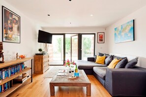 A modern living room with a sofa, coffee table, and bookshelf. - The Akerman Road Hideaway (London)