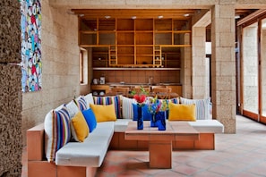 A modern interior with a sectional sofa, a coffee table, and a kitchen area with wooden shelves. - Casas Bioclimáticas Iter El Pueblo (Granadilla de Abona)
