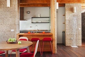 Eine moderne Küche mit einer Holztheke, roten Barhocker und einem Esstisch mit einer Schale grüner Äpfel.