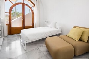 Ein Schlafzimmer mit einem Bett, einer Couch und einem großen Bogenfenster.