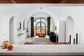 Ein modernes Interieur mit Essbereich, Blick durch einen Bogen und einer Sitzecke mit Tisch und Stühlen.