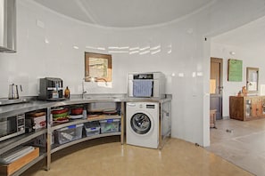 Cocina compacta con lavadora integrada, cafetera y ventana con vistas.