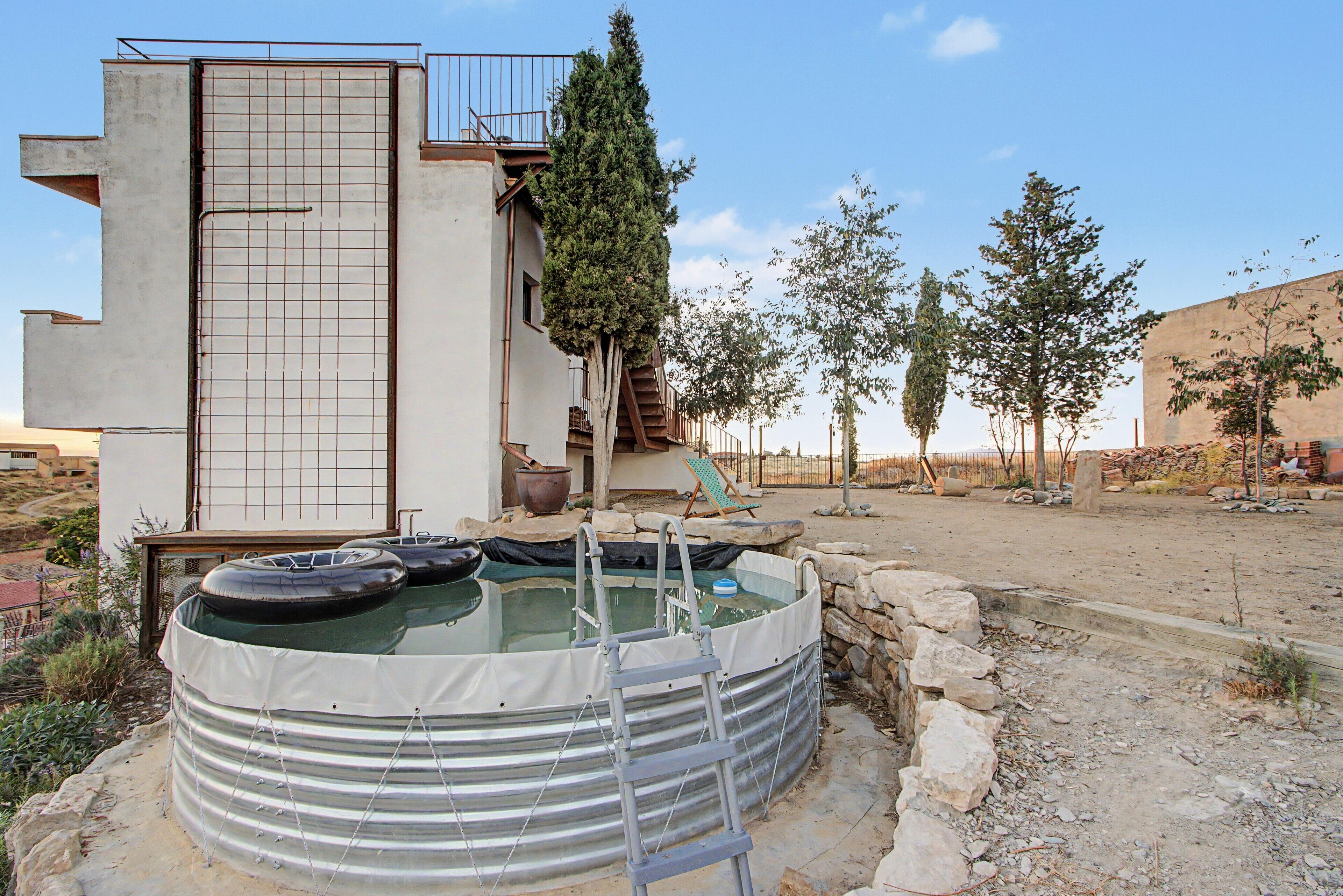 Una piscina con flotadores, una escalera y un muro de piedra.