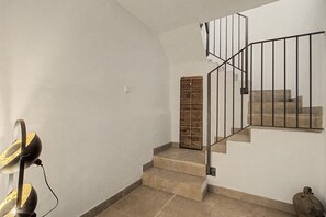 Una escalera con barandilla metálica, un interruptor de luz en la pared y una puerta de fibras.