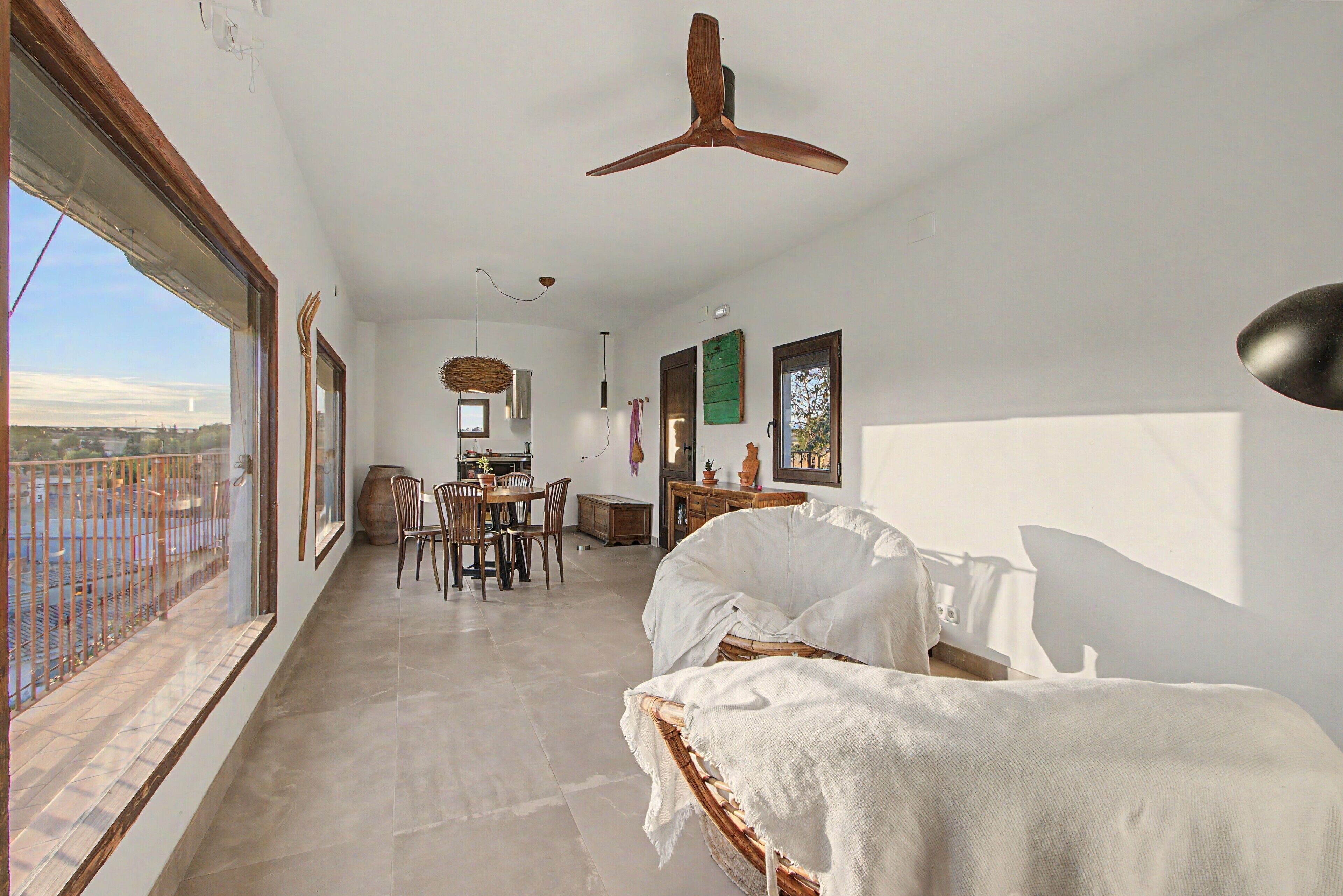 Una habitación amplia con una cama grande, un comedor y vistas desde un balcón.
