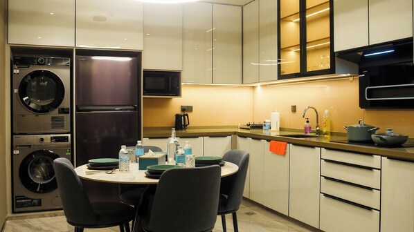 A modern kitchen with built-in appliances, a dining area with chairs, and a countertop with various items. - Imperial Residence KLCC- JD Home (Wilayah Persekutuan)