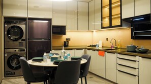 Een moderne keuken met inbouwapparatuur, een eethoek met stoelen en een aanrecht met diverse spullen.