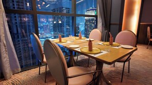 A dining area with a city view, a table set for four, and modern chairs. - Imperial Residence KLCC- JD Home (Wilayah Persekutuan)