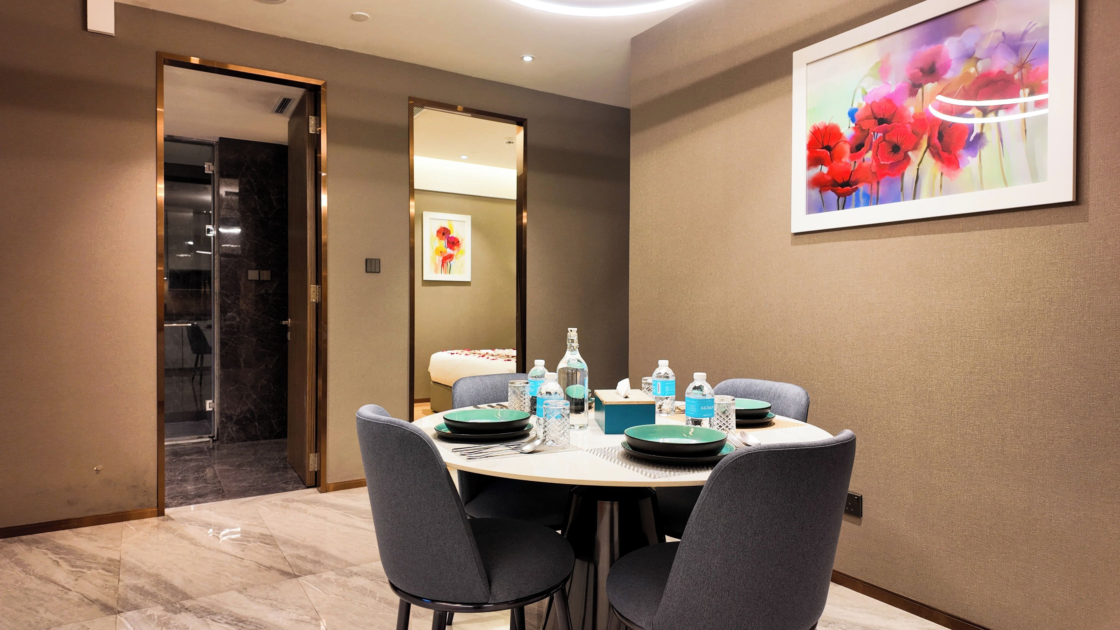 A hotel dining room with a round table set for four, equipped with plates, glasses, and water bottles.
