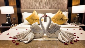 A hotel room with a bed featuring a swan towel arrangement and rose petals. - Imperial Residence KLCC- JD Home (Wilayah Persekutuan)