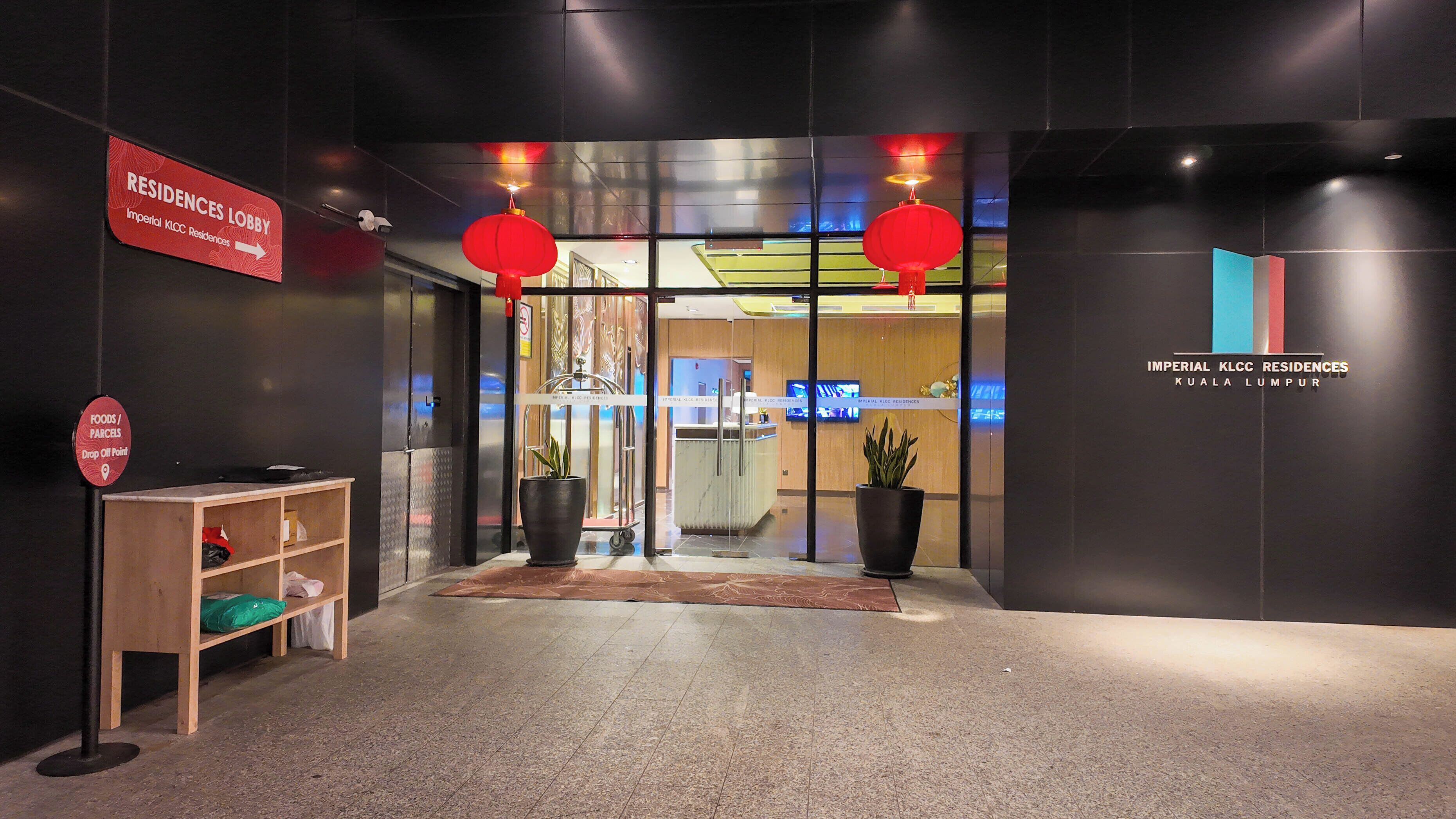 The entrance to Imperial KLCC Residences with a reception desk, a sign indicating the lobby, and a drop-off point for food and parcels.
