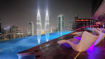 An infinity pool with a view of the Petronas Towers at night.